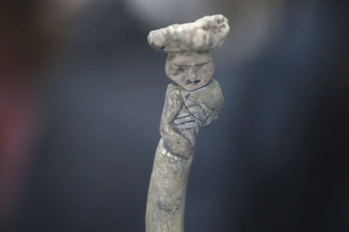 Object from Vichama, with a human like figure atop a snake. to snakes