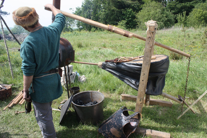 A reenactor operates a traditional bellows during a Viking Festival demonstration at Delamont Country Park